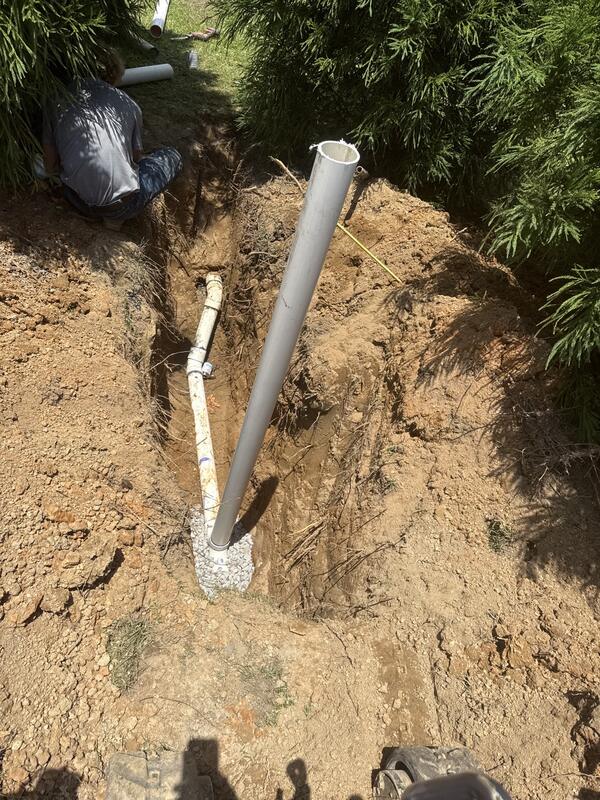 New sewer cleanout riser set over a gravel bedded line in an open trench