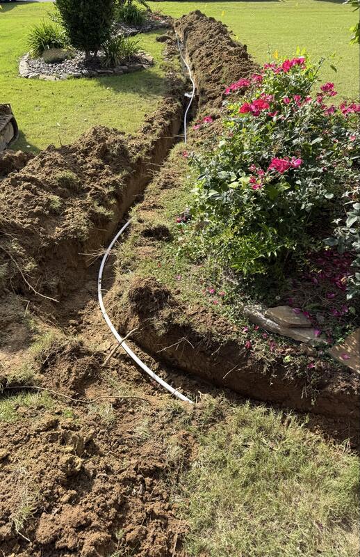 New water line laid in a narrow trench routed carefully around a flower bed